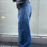 Jean azul de tiro medio con corte recto, confeccionado en denim con gran estampado en la parte trasera simulando alas.