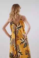 Vestido largo amarillo con estampado de hojas de palmera en blanco y negro, con breteles finos y botones en el frente.