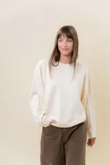 Buzo de tejido de punto color crema, con cuello redondo y mangas amplias, de corte relajado.