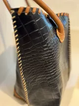 Bolso shopper de cuero azul con textura crocco, manijas largas marrones y costuras artesanales visibles en los bordes.