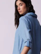 Blusa de lyocell color azul claro, con cuello camisero, escote en V con tapeta de botones y mangas largas con presilla para regular el largo.