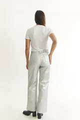 Pantalón plateado de cuerina, corte recto y cinco bolsillos funcionales.