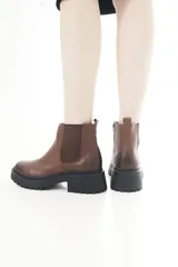Botas de cuero marrón con suela track negra, diseño estilo Chelsea con inserciones elásticas laterales y cierre lateral.