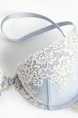 Soutien push-up con aros y copas acolchadas, confeccionado en malla color celeste con aplicaciones de encaje floral en tono crema. Cuenta con breteles ajustables y cierre de corchetes en la espalda.