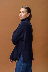 Sweater de punto color azul marino con cuello alto y diseño holgado. Presenta mangas con hombros caídos, terminaciones acanaladas y apliques de líneas orgánicas en relieve de color blanco que forman figuras florales en el frente y las mangas.