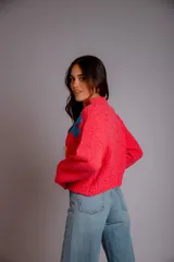 Buzo de punto color fucsia, con cuello redondo, manga larga y bordado de flores en amarillo y azul en el frente.
