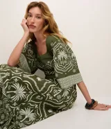 Pollera larga (midi/maxi) de tejido piqué, color verde oscuro con estampado en blanco/beige de motivos tropicales y palmeras. Presenta un diseño con fruncido en la parte inferior.