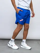 Short deportivo azul con escudo del Club Nacional de Football en la pierna derecha y detalles tricolor.