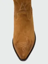 Botas estilo western de gamuza color tostado, con diseño de caña media y bordados decorativos en forma de flores. Presentan un detalle de cordón con borlas en el tobillo y taco cuadrado.