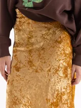 Pollera midi de corte al bies confeccionada en terciopelo con acabado brillante y textura arrugada.