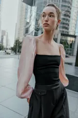 Body de escote cuadrado con cuerpo en tejido elástico negro y mangas largas abullonadas en tejido satinado color rosado con puños elásticos.