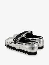 Zapato náutico plateado con flecos y cordones negros, y suela track negra.