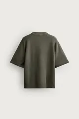 Remera de corte relaxed fit, color mostaza, con cuello redondo y mangas ranglán cortas.