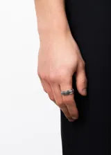 Anillo de acero quirúrgico color plateado con banda giratoria y diseño de guarda griega en negro.