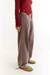 Pantalón de jean de tiro bajo, color marrón con efecto lavado, de corte recto y holgado. Presenta cordones de ajuste en los tobillos para modificar la silueta y bolsillos laterales.