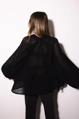 Camisa holgada de popelina de algodón con diseño de rayas verticales en tonos rosado, blanco y negro. Presenta cuello alto con volado, hombros caídos y mangas anchas abullonadas con puños ajustados. Cierre frontal con botones.