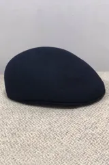 Gorra inglesa de lana color verde militar, con diseño clásico de visera corta y estructurada.