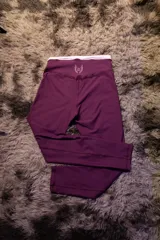 Calza deportiva larga color morado oscuro, tiro alto, con pretina blanca y logo de alas bordado en blanco en la parte trasera de la cintura.