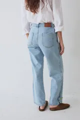 Pantalón tipo bombacha de campo confeccionado en denim azul. Presenta pinzas frontales, cierre de botones en los tobillos para ajustar la silueta y costuras reforzadas.
