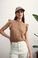 Camisa marrón claro sin mangas con cuello mao y volados en la pechera y los hombros.