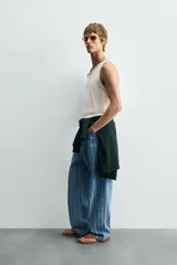 Camiseta tipo tank top de corte slim fit, color blanco hueso, con cuello redondo amplio y sisas terminadas con pespunte contrastante en color oscuro.