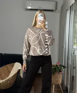 Sweater de tejido de punto con diseño abstracto de líneas blancas sobre fondo de color sólido. Presenta un corte clásico y textura suave.
