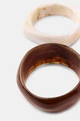 Pack de tres pulseras rígidas de resina en tonos tierra, con acabados lisos y marmolados.