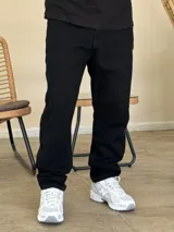Pantalón jean de corte recto y holgado, color negro, con diseño de cinco bolsillos y cierre frontal con botón y cremallera.