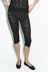 Leggings capri negros confeccionados en tejido de encaje, con tiro alto, cintura elástica y bajo acabado en ondas.