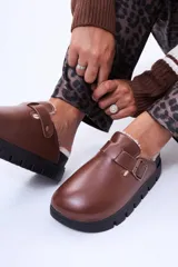 Sueco de cuero sintético negro con interior forrado en piel sintética. Presenta una tira ajustable con hebilla metálica en el empeine y una suela de plataforma dentada.