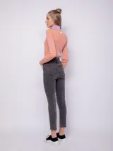 Pantalón de jean chupín gris oscuro con cuatro bolsillos, botón y cierre metálicos.