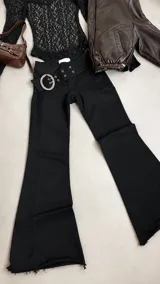 Pantalón oxford negro de tiro bajo, con detalle de doble cinturón con ojales metálicos y hebilla grande circular plateada.
