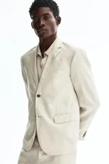 Blazer de lino liviano color beige, con solapas de muesca finas, botonadura sencilla de un botón, bolsillos con solapa en el frente y bolsillo superior ojal.