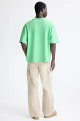 Remera de algodón color verde con cuello redondo acanalado, hombros caídos y bordado pequeño en el pecho con la palabra Golden.
