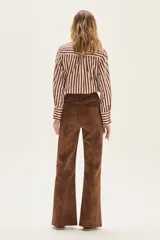 Camisa de manga larga con cuello y puños, confeccionada en tejido de rayas verticales en tonos crema y bordó. Presenta un bolsillo de parche en el pecho con un bordado exclusivo.