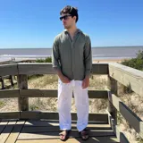 Camisa de manga larga color beige claro, con textura de lino arrugado y corte boxy. Presenta cuello camisero y cierre frontal de botones.