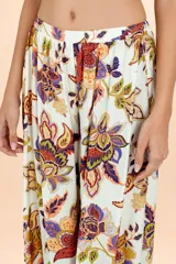 Pantalón tipo aladín con cintura elástica y puños ajustados en los tobillos. Presenta un estampado botánico multicolor sobre fondo blanco.