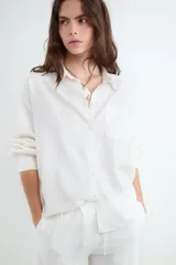 Camisa de manga larga color negro, de corte holgado, cuello camisero, cierre frontal con botones y un bolsillo aplicado en el pecho. Confeccionada en mezcla de lino y viscosa.