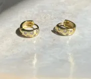 Par de aros tipo argolla pequeños, dorados con incrustaciones de circonitas blancas.
