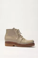 Bota acordonada de cuero vacuno con acabado charol color suela, con suela de goma tipo crepe y costuras reforzadas.