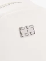 Mochila blanca de poliuretano con acabado texturizado, cierre de cremallera, asa superior, correas ajustables, bolsillo interior con cremallera, bolsillo exterior con cremallera e insignia de Tommy Jeans en la parte delantera.