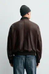 Cazadora bomber de corte regular confeccionada en piel encerada color marrón oscuro. Presenta cuello, puños y bajo en tejido rib elástico, cierre frontal con cremallera y bolsillos laterales con cierre.