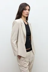 Blazer sastrero color beige melange confeccionado en lino, con solapas clásicas y cierre frontal abierto.