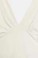 Top marrón con textura, escote en V pronunciado, mangas amplias por debajo del codo tipo capa y detalles de pliegues laterales.