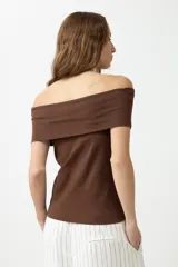 Remera de color marrón con escote bardot, diseño ajustado al cuerpo y mangas cortas.