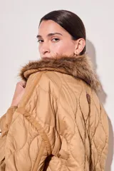 Campera color camel con diseño acolchado, cierre con botones a presión, cuello de piel sintética desmontable, bolsillos delanteros y puños ajustables con lazo.