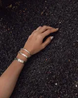 Pulsera tipo esclava abierta con diseño rústico y acabado irregular, fabricada en bronce y alpaca.