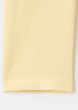 Chaleco de punto fino color amarillo claro, de corte recto, con cuello redondo, manga larga y cierre delantero de botonadura completa.