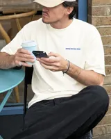 Remera de algodón color crema, de corte oversize, con cuello redondo y mangas cortas. Presenta el texto "BOHEMIAN DSG" bordado en azul en el pecho.