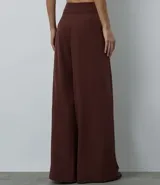 Pantalón de sastrería modelo pantalona, de corte amplio y tiro alto, con cintura lisa y pliegues frontales. Confeccionado en tejido de poliéster con elastano.